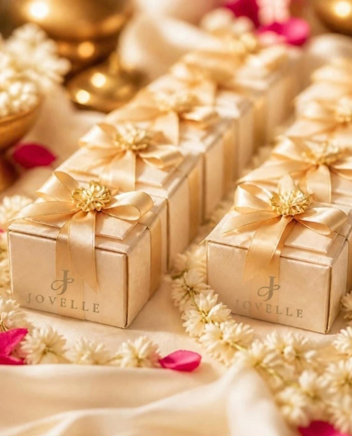 Rows of ivory wedding favour boxes with gold ribbons and jasmine
